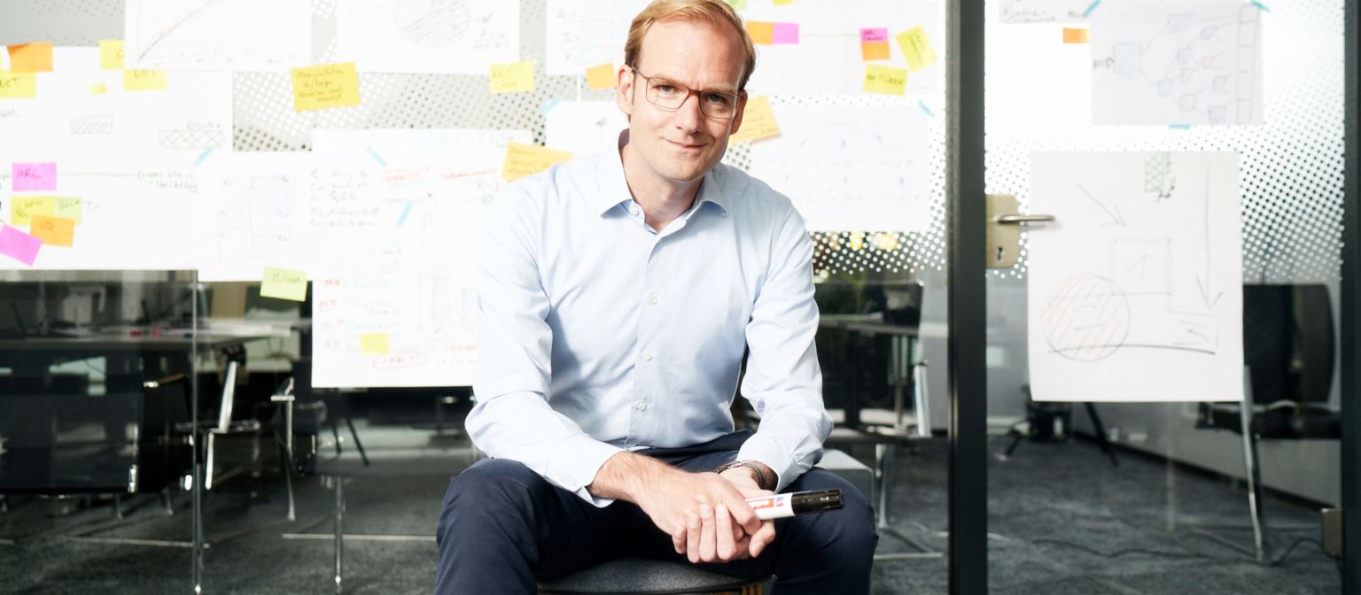 Receivables purchasing: Matthias Schmidt, Head of Operational Debt Purchase at EOS Group, sits in front of a wall covered in post-its and other notes.