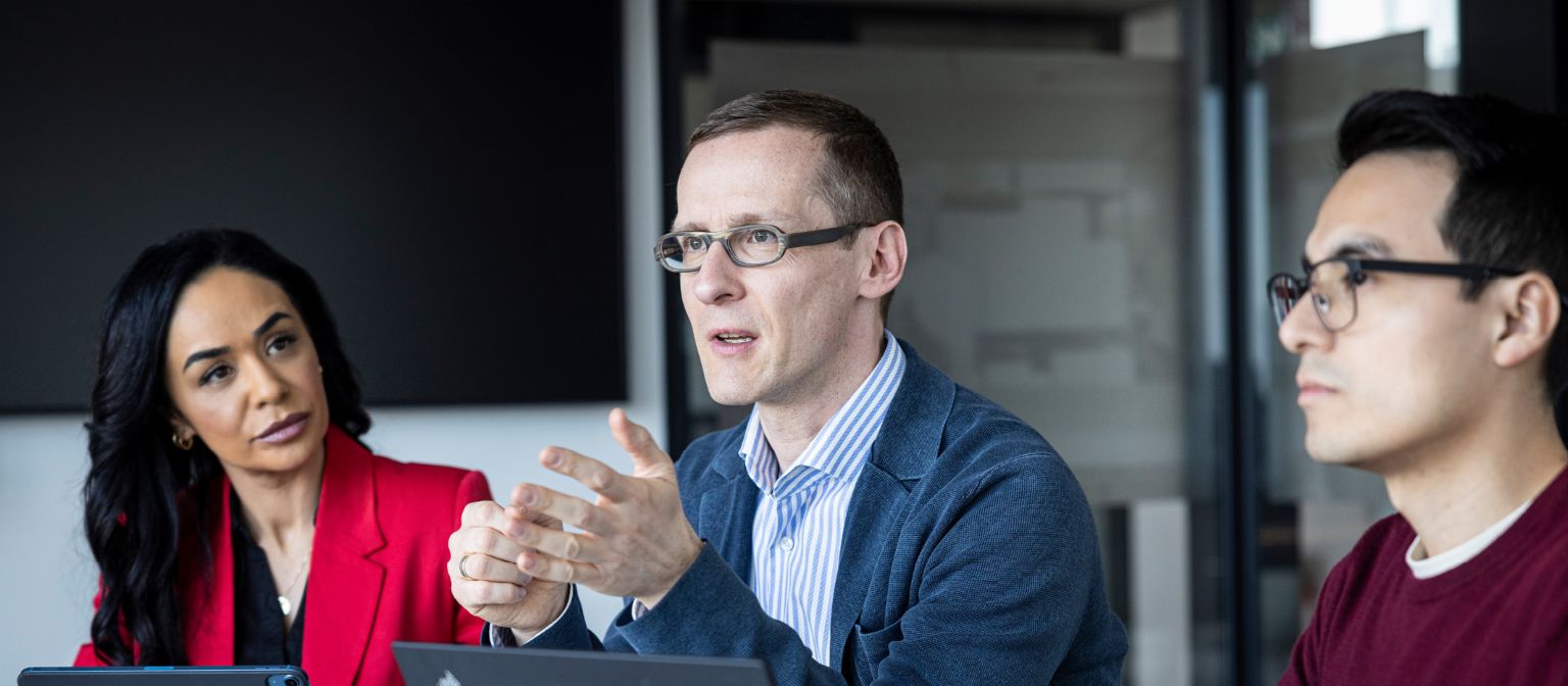 Tři lidé vedou rozhovor v kanceláři.