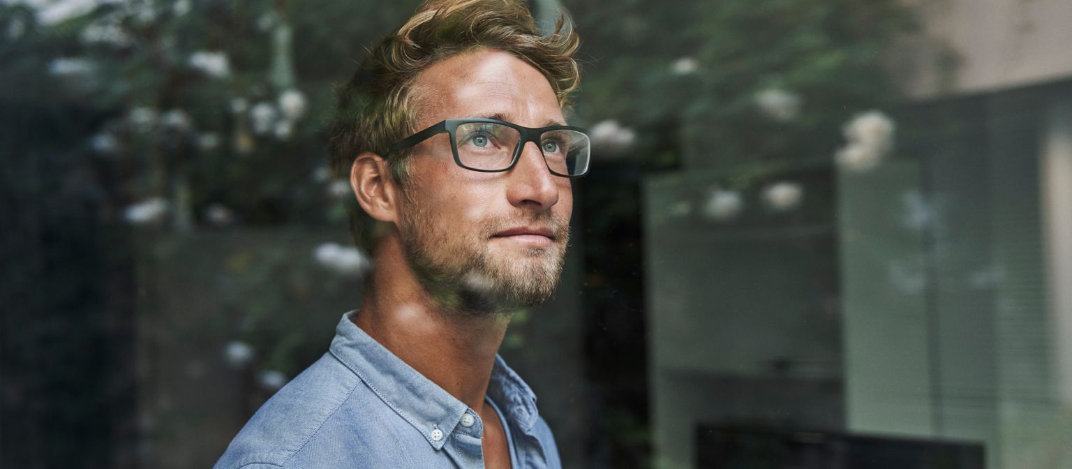 Mladý muž generace Z úzkostlivě vykukuje z okna.