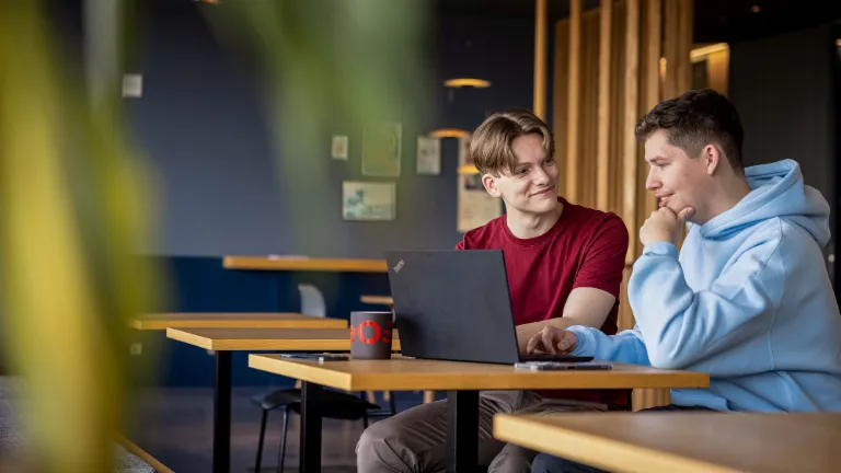 Dva zaměstnanci spolupracují u notebooku a podporují partnerství a férovost na pracovišti.