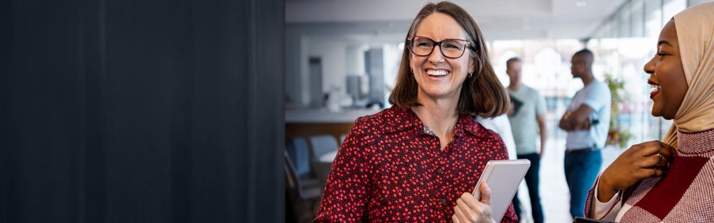 Dvě šťastné ženy si neformálně povídají v kanceláři