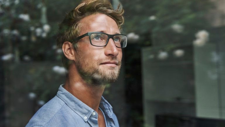 Mladý muž generace Z úzkostlivě vykukuje z okna.